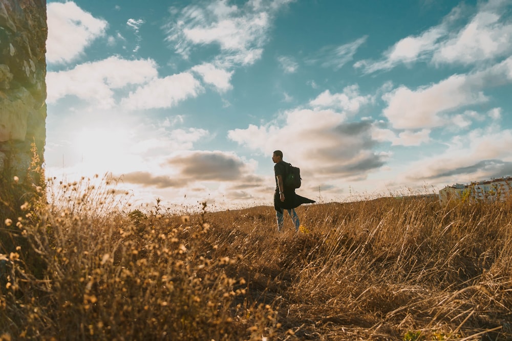 a man standing in a field holding a surfboard