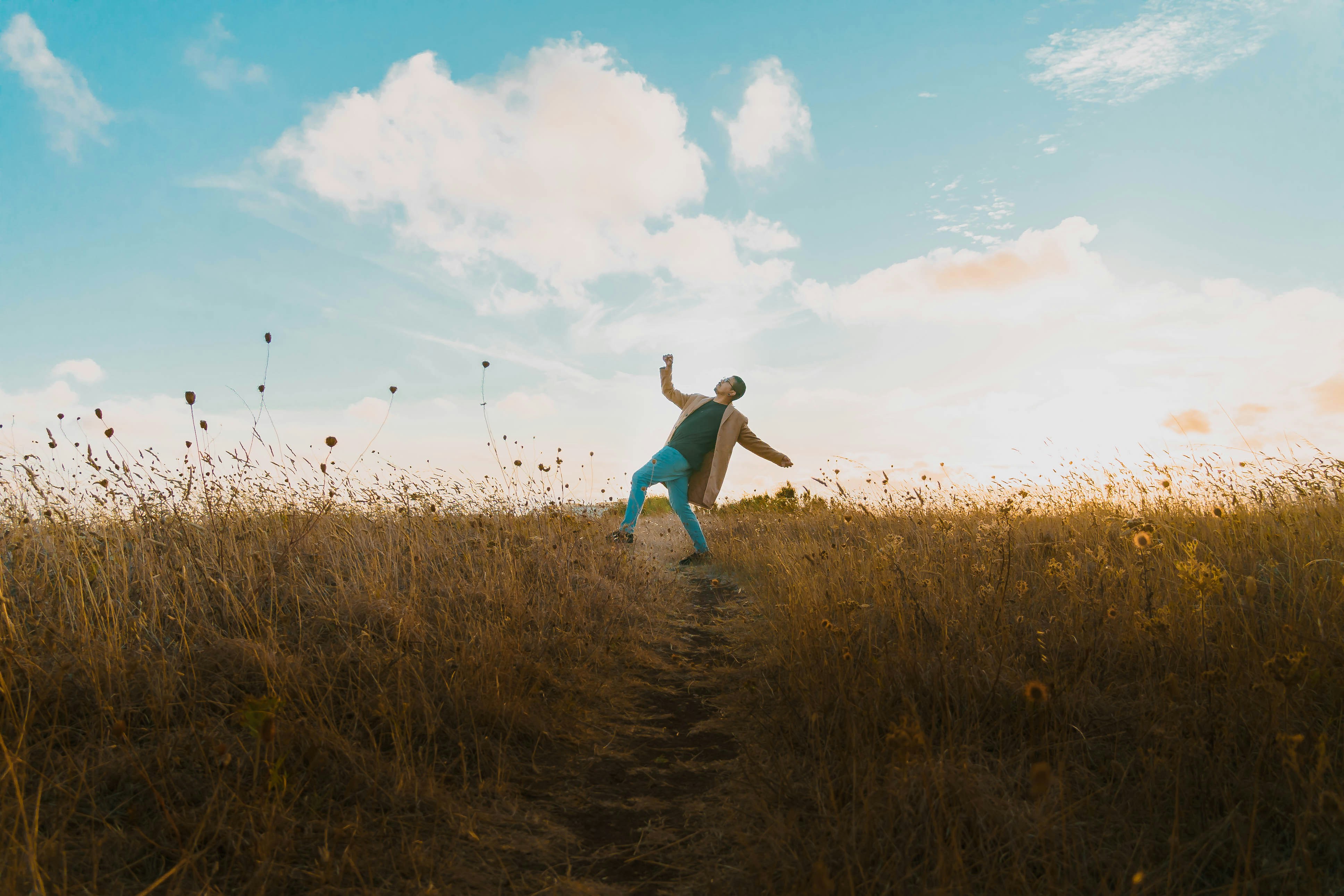 a man standing on a dirt road in a field, 
