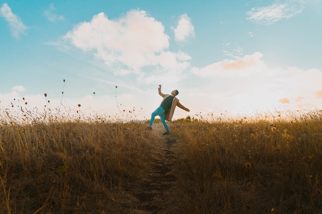 a man standing on a dirt road in a field,