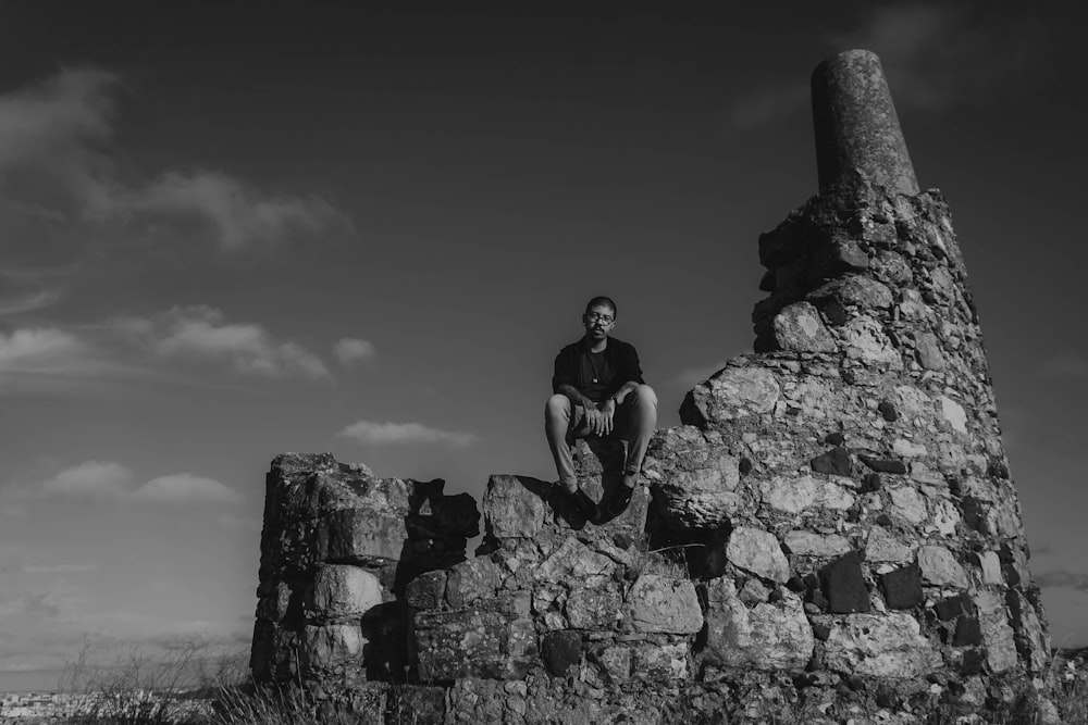 a man sitting on top of a stone building