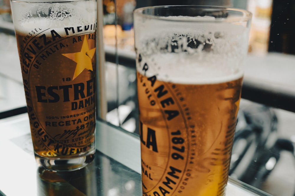 two glasses of beer sitting on a table