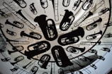 A circular ceiling installation features a variety of musical instrument silhouettes, including tubas, trumpets, and trombones. The instruments are suspended uniformly, creating an artistic and dynamic visual effect. The background includes ornate architectural details, such as carved molding and skylight structures.