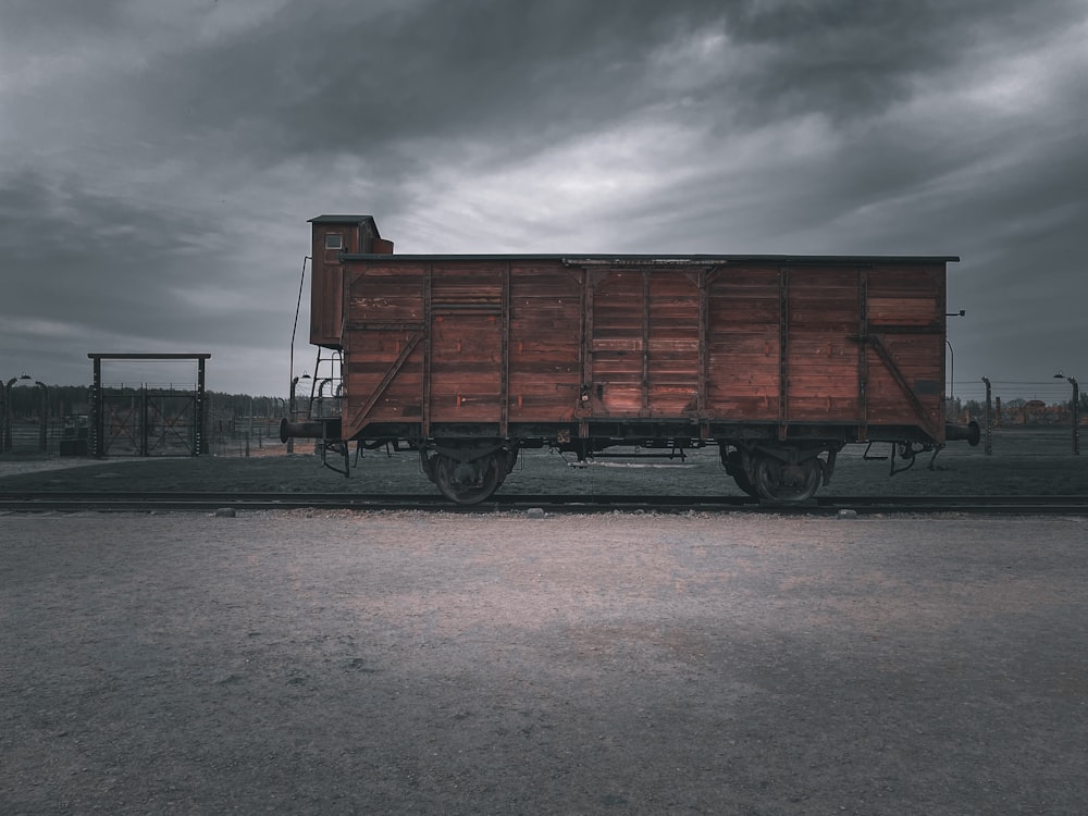 a train car sitting on the tracks under a cloudy sky