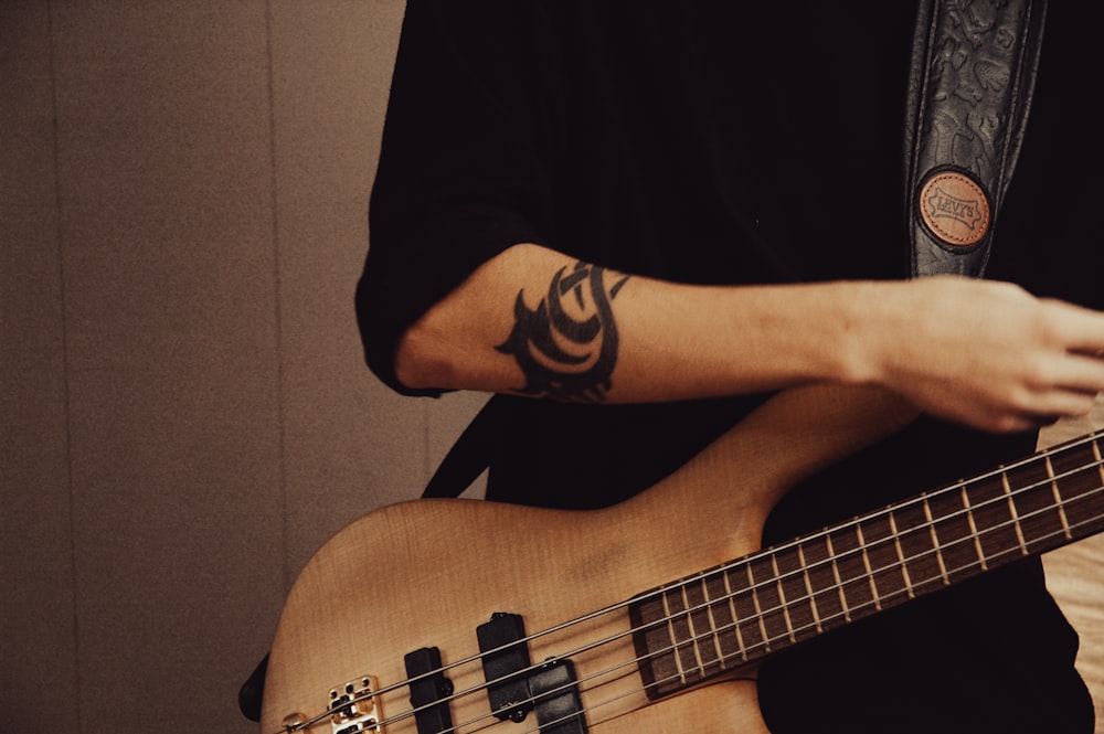 a man with a tattoo on his arm playing a bass guitar