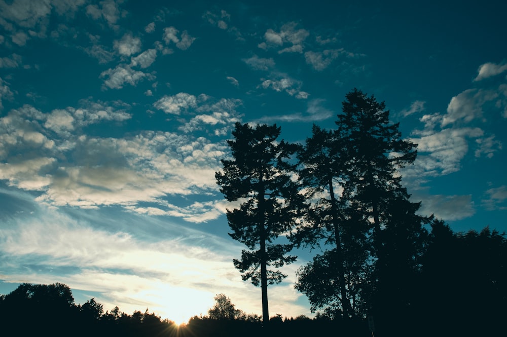 the sun is shining through the clouds over the trees