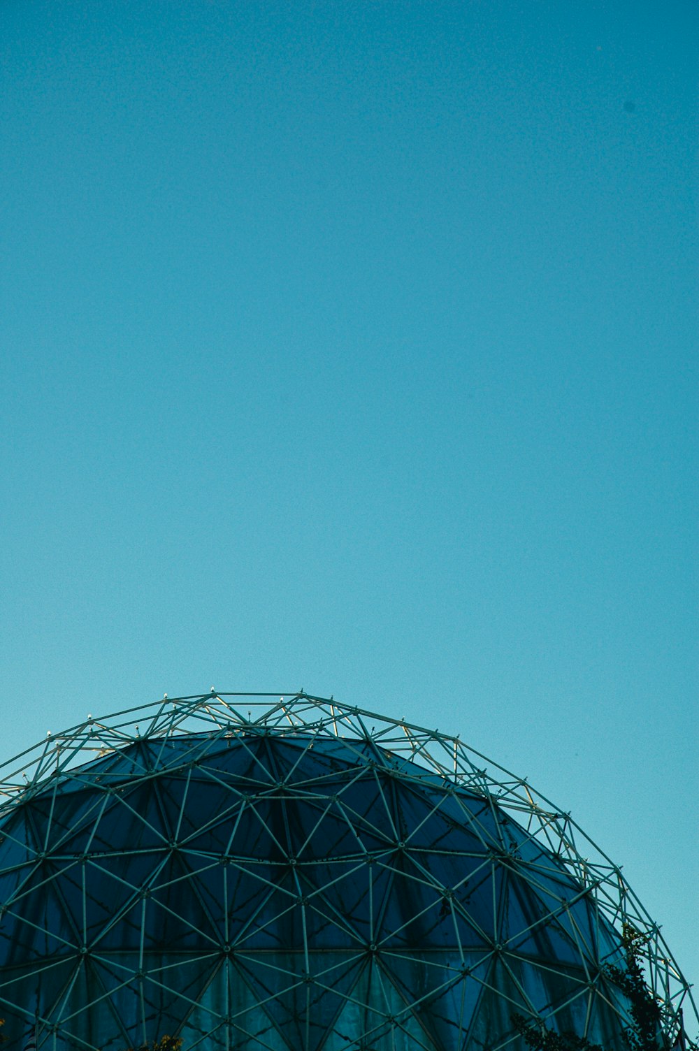 an airplane flying over a large structure under a blue sky