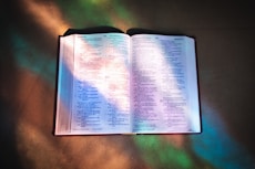 an open bible on a table in the sunlight