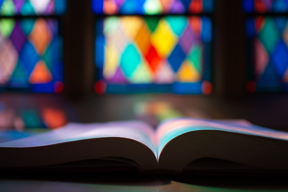 an open book sitting in front of a stained glass window