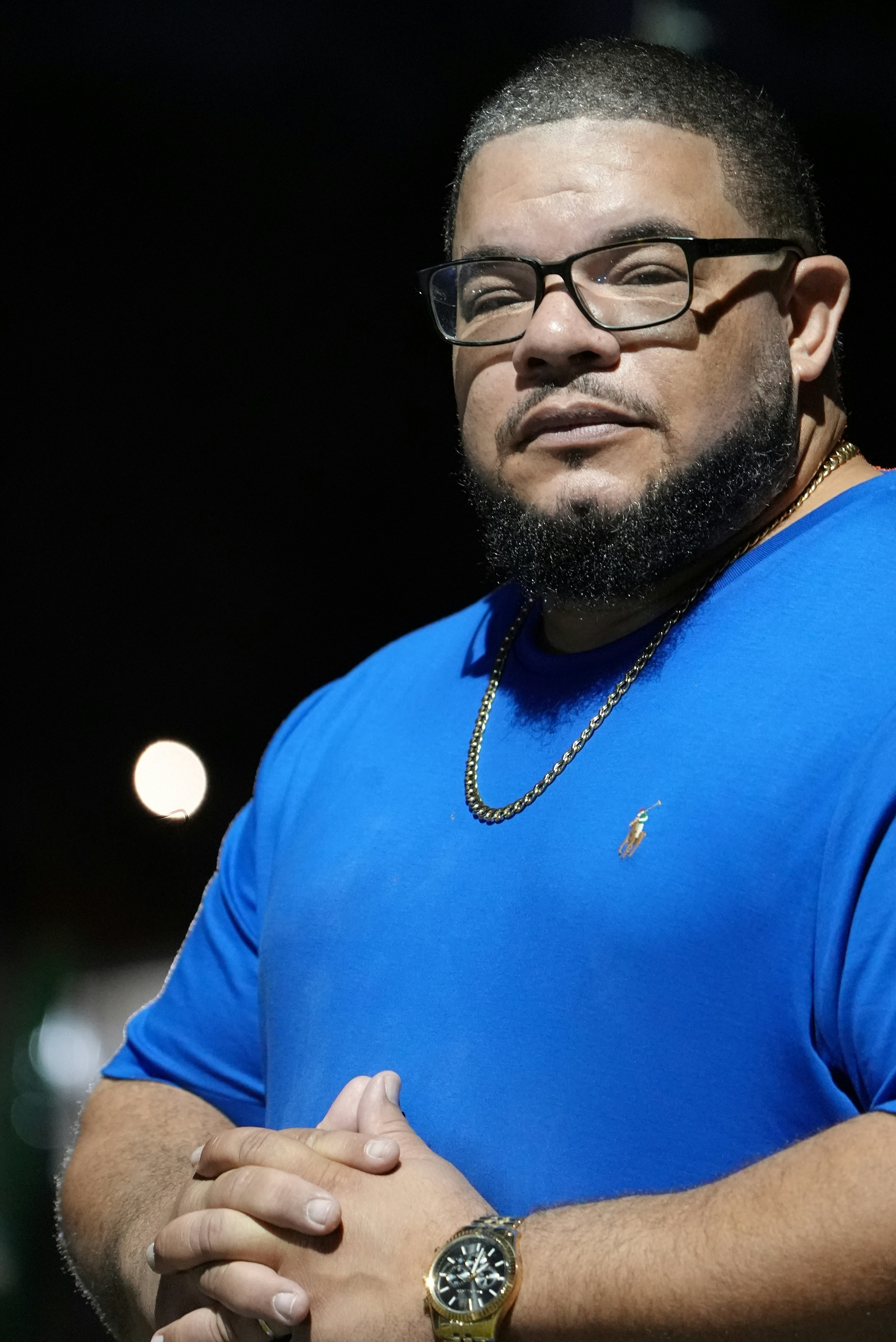 a man with a beard and glasses standing with his arms crossed