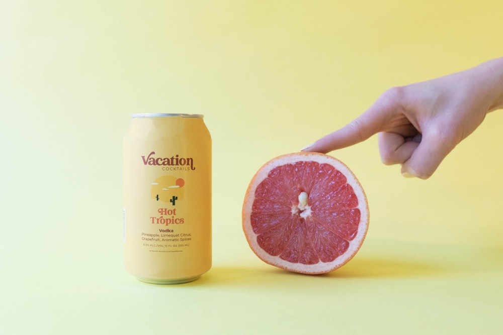 a grapefruit and a can of vacation on a yellow background