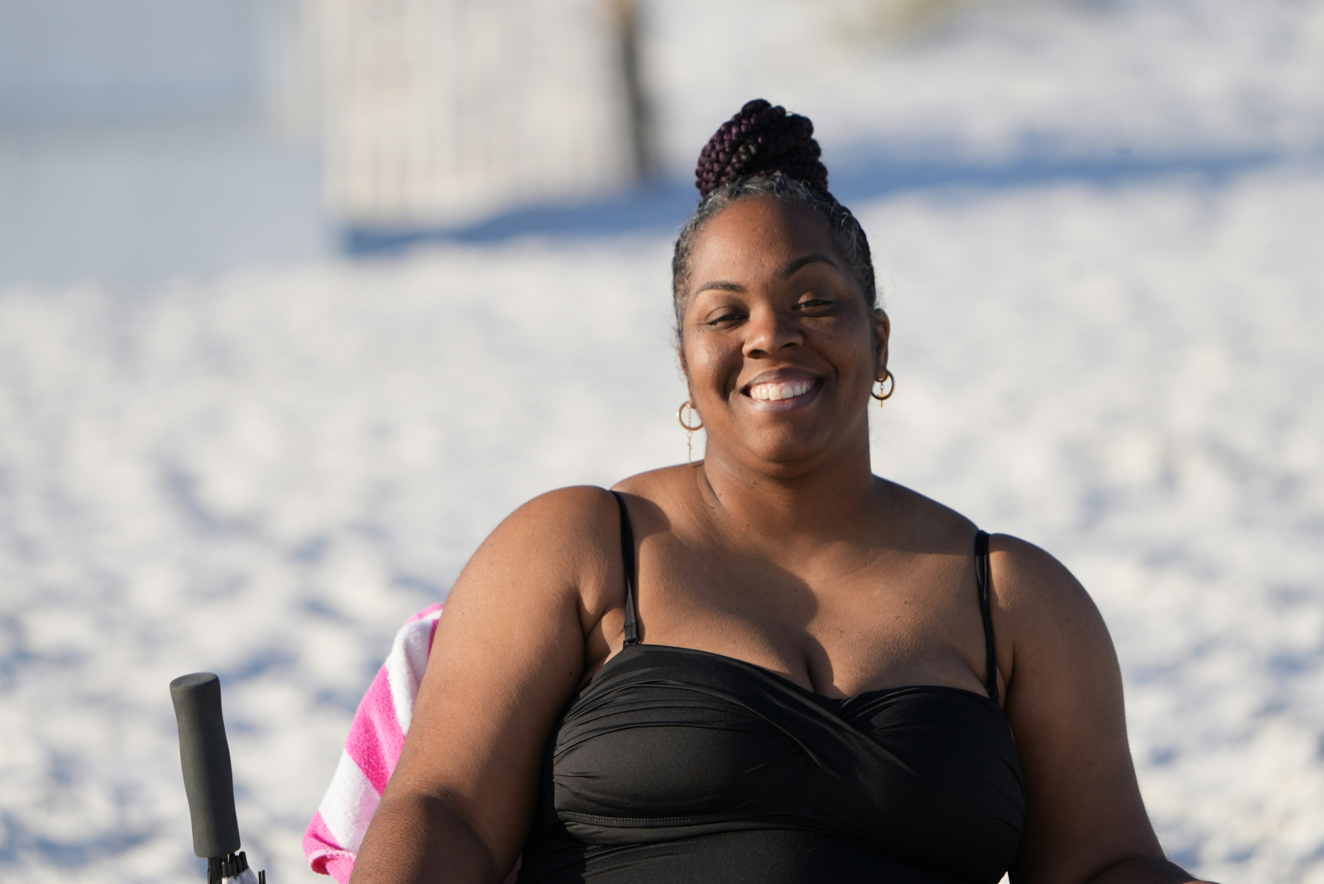 a woman in a black bikini top sitting on the beach