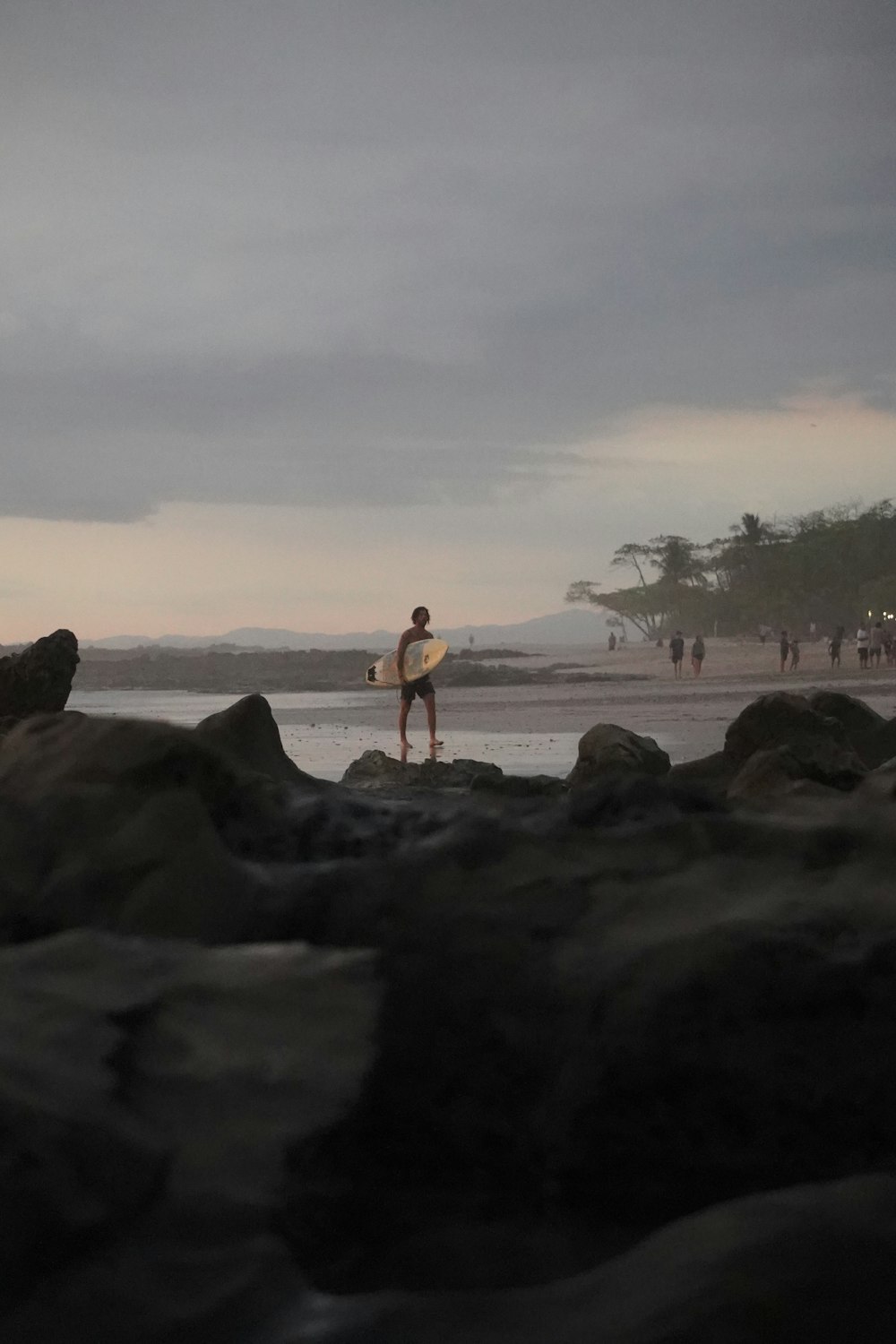 a man standing on a beach holding a surfboard