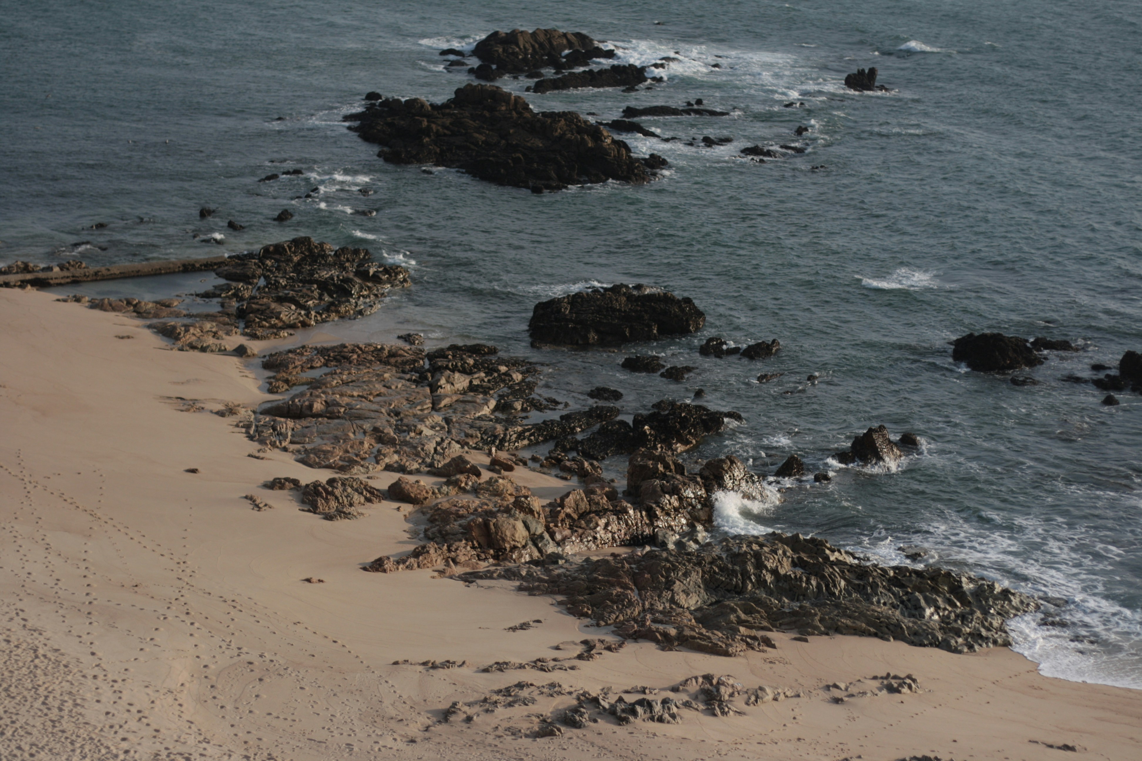 a sandy beach next to a body of water