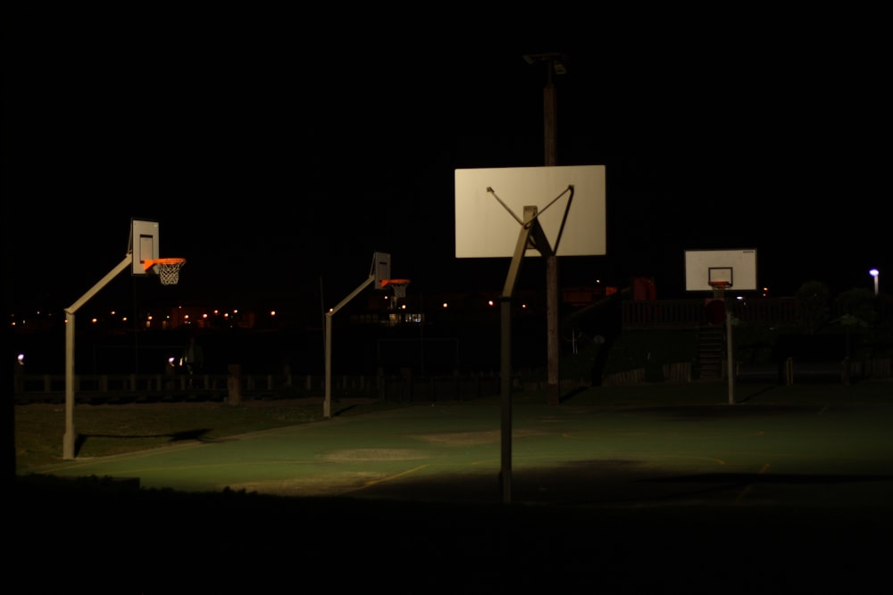 a basketball court at night with a basketball going through the hoop