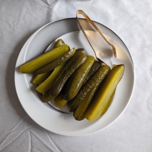 pickles and serving tongs on a white plate