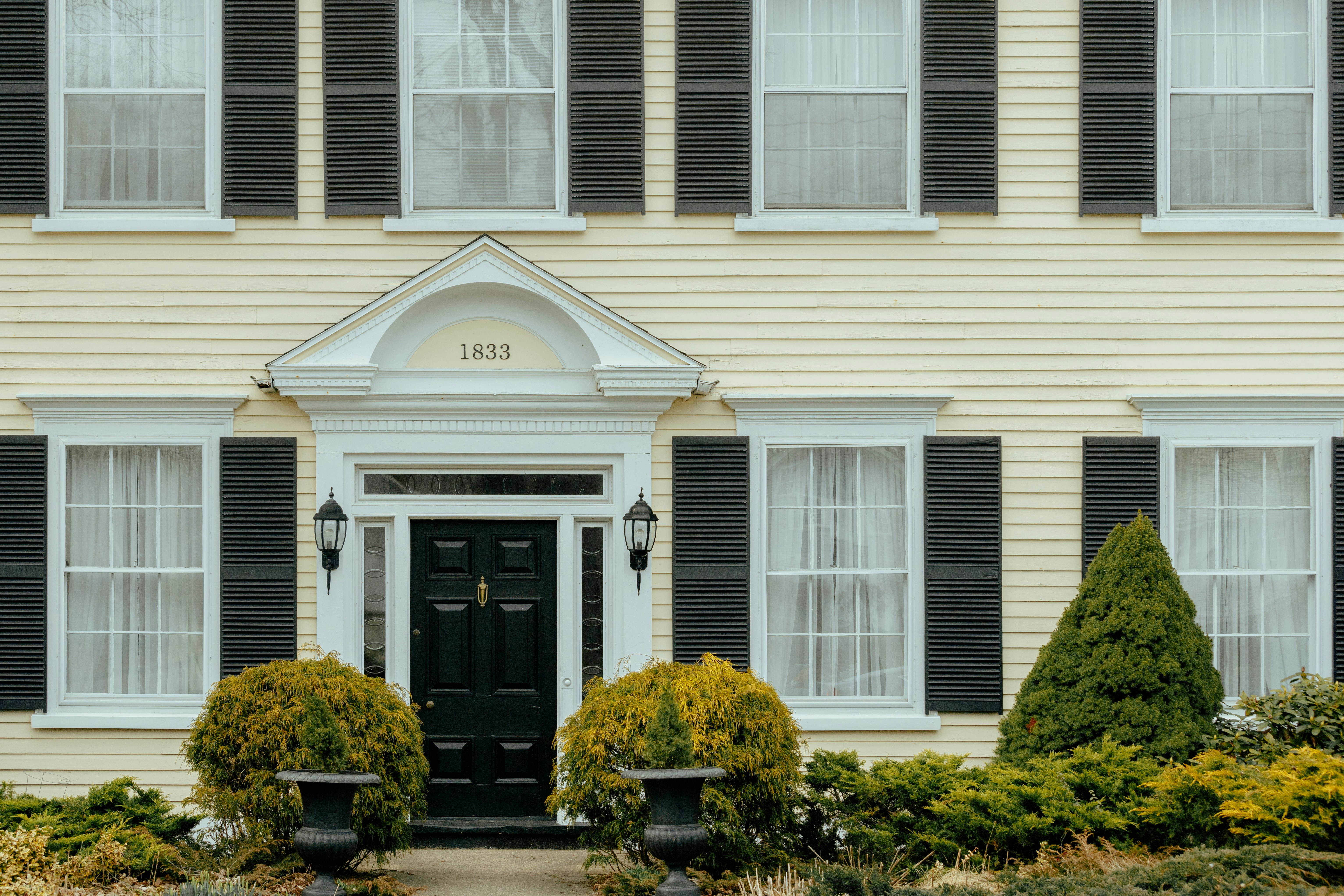 a yellow house with black shutters and a black door