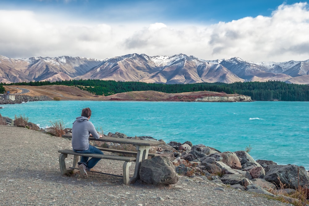 a person sitting on a bench near a body of water