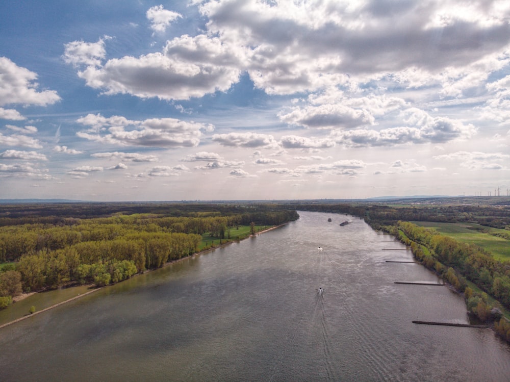 a body of water surrounded by trees and clouds