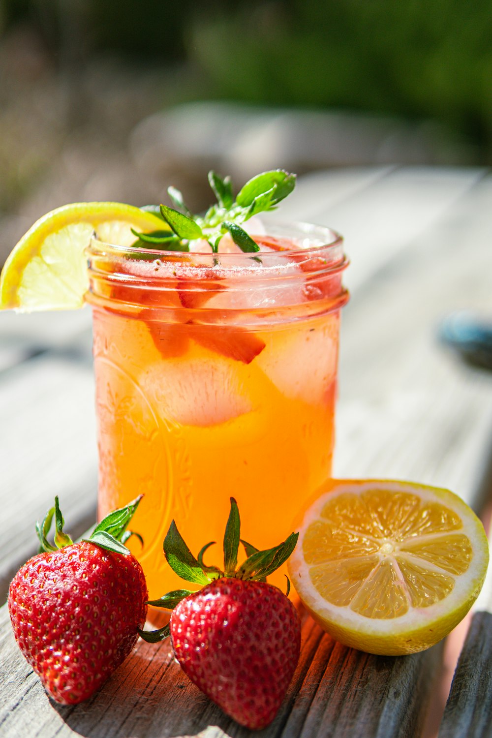 a glass of lemonade and strawberries on a wooden table