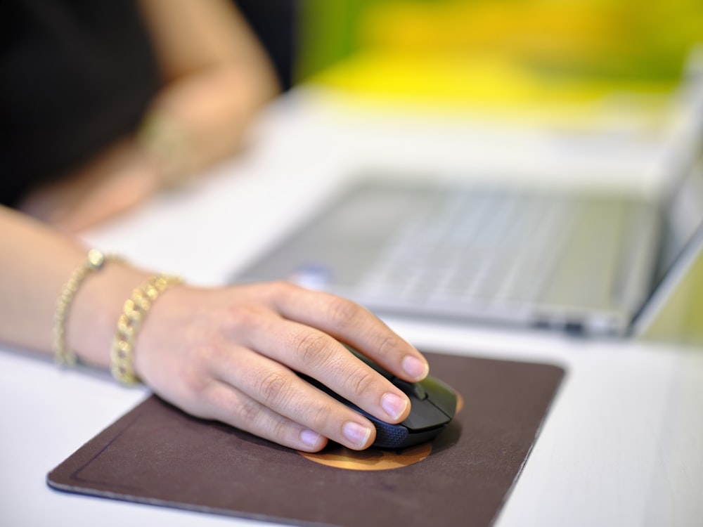 a woman's hand on a mouse pad next to a laptop