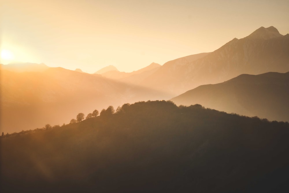 the sun is setting over the mountains in the distance