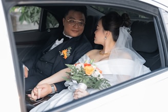 a bride and groom sitting in the back of a car