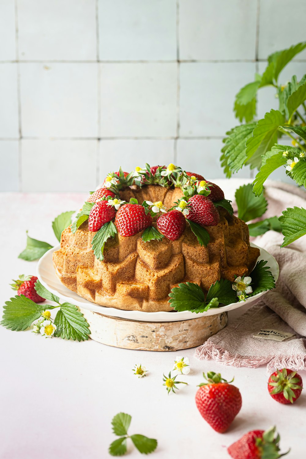 a bundt cake with strawberries and flowers on a plate