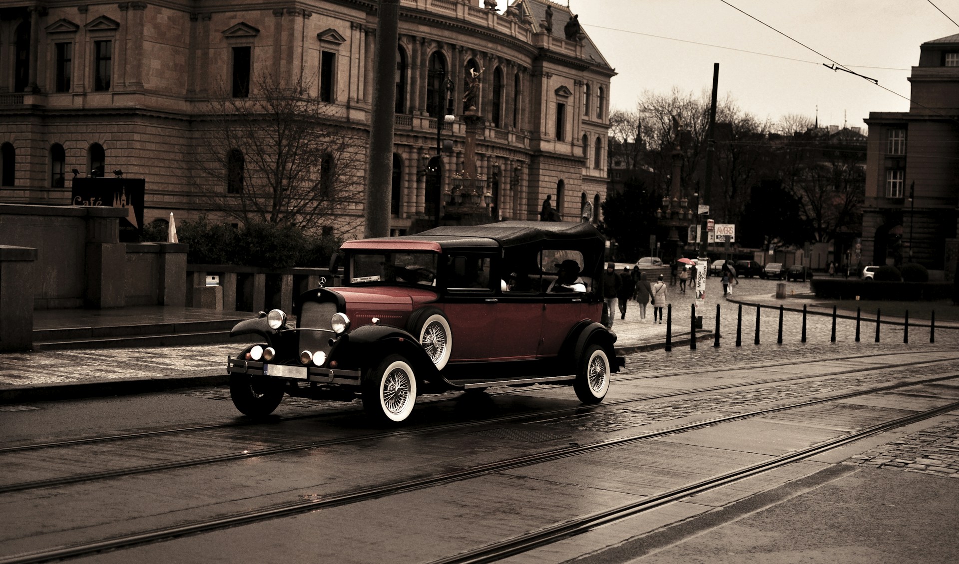 an old fashioned car driving down a wet street