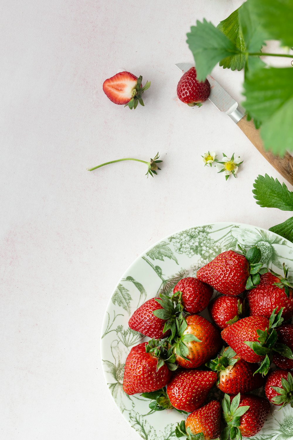 a plate of strawberries on a white table