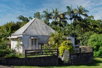 a small house with a fence and trees in the background