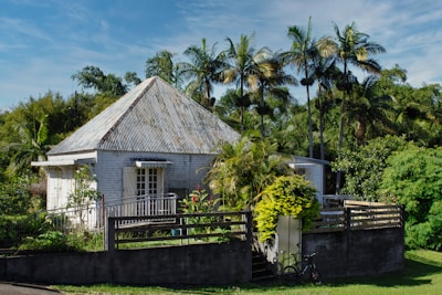 a small house with a fence and trees in the background