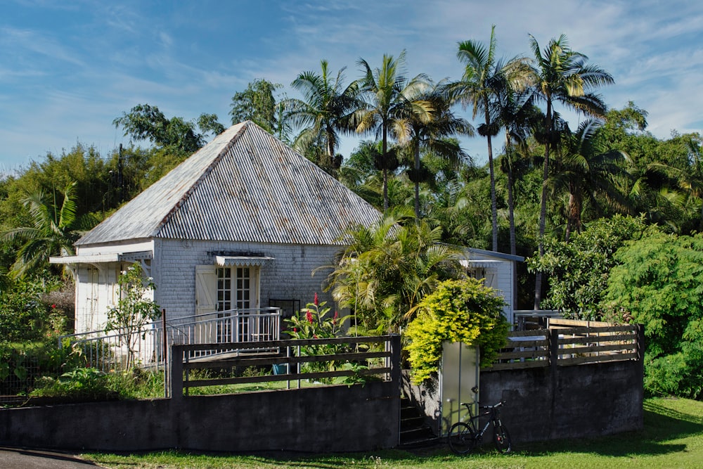 a small house with a fence and trees in the background