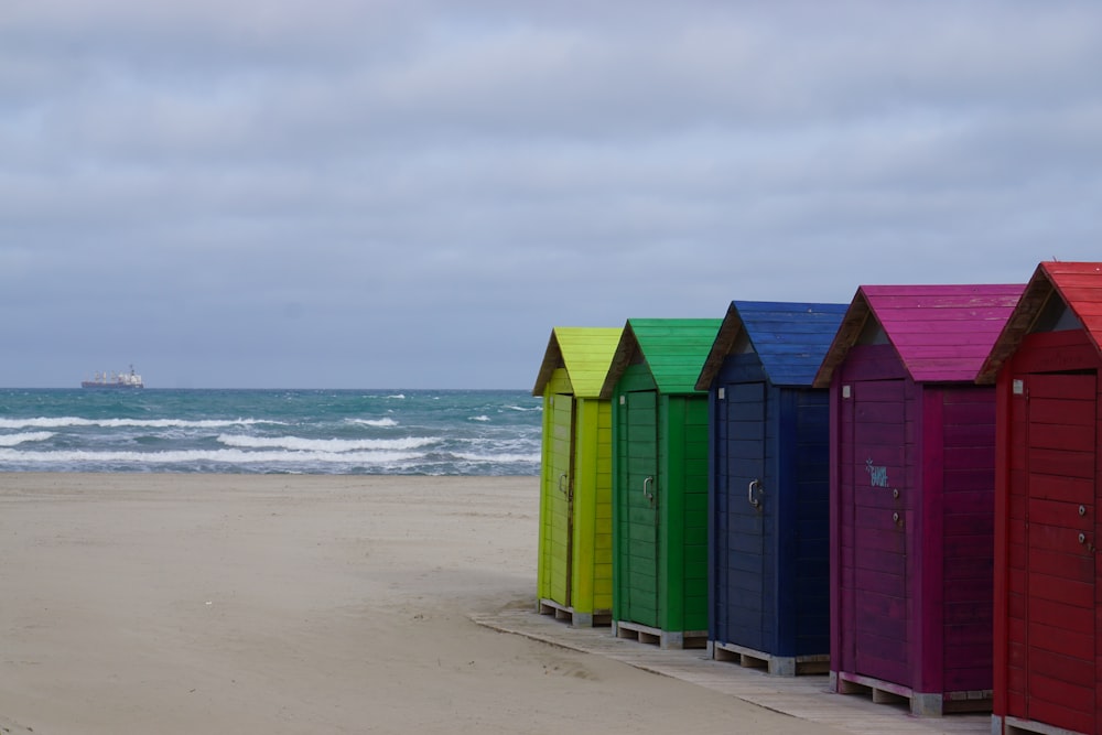 a row of colorful beach huts sitting on top of a sandy beach