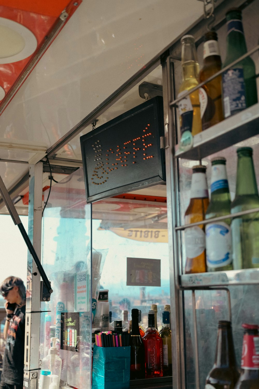 a man standing in front of a store filled with bottles