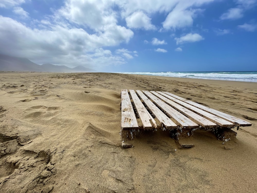 a wooden bench sitting on top of a sandy beach