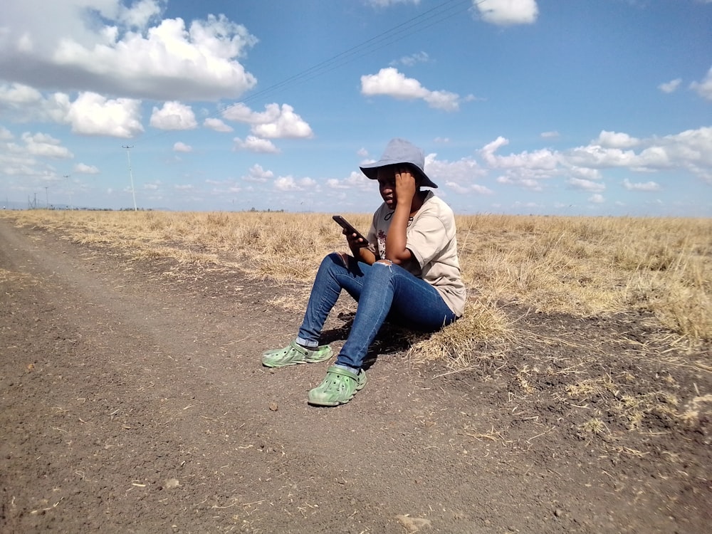 a woman sitting on the side of a dirt road