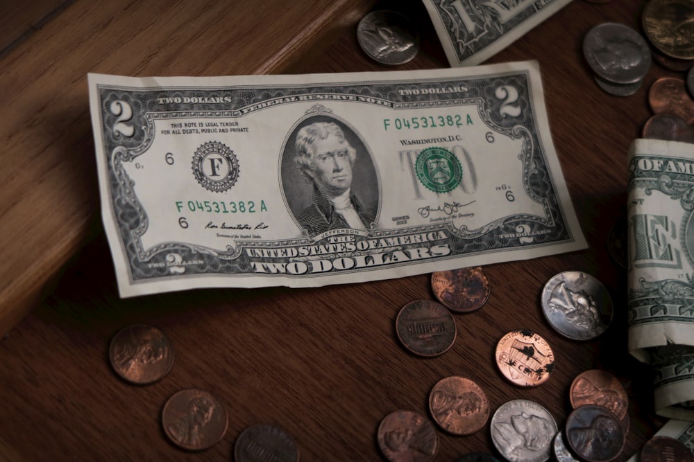 a roll of one hundred dollars sitting on top of a wooden table