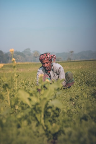 a man kneeling in the middle of a field
