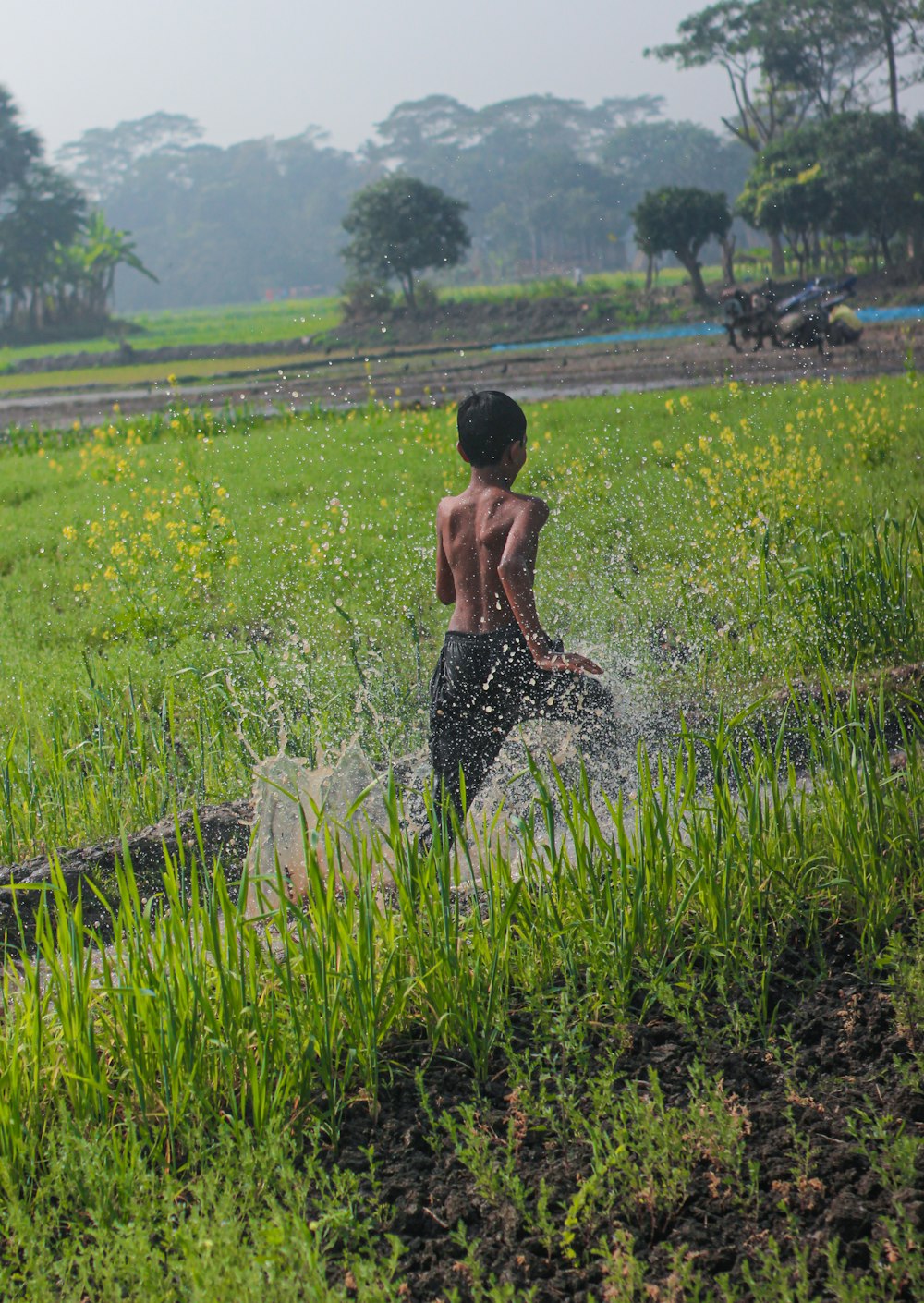 a young boy splashes water on his body in a field