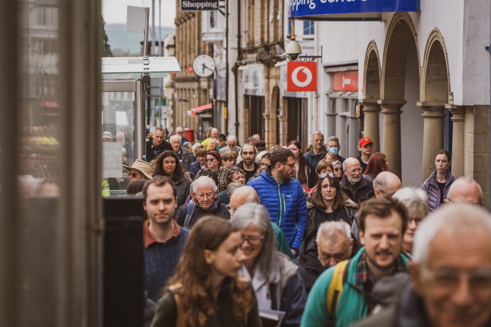 a crowd of people walking down a street next to tall buildings