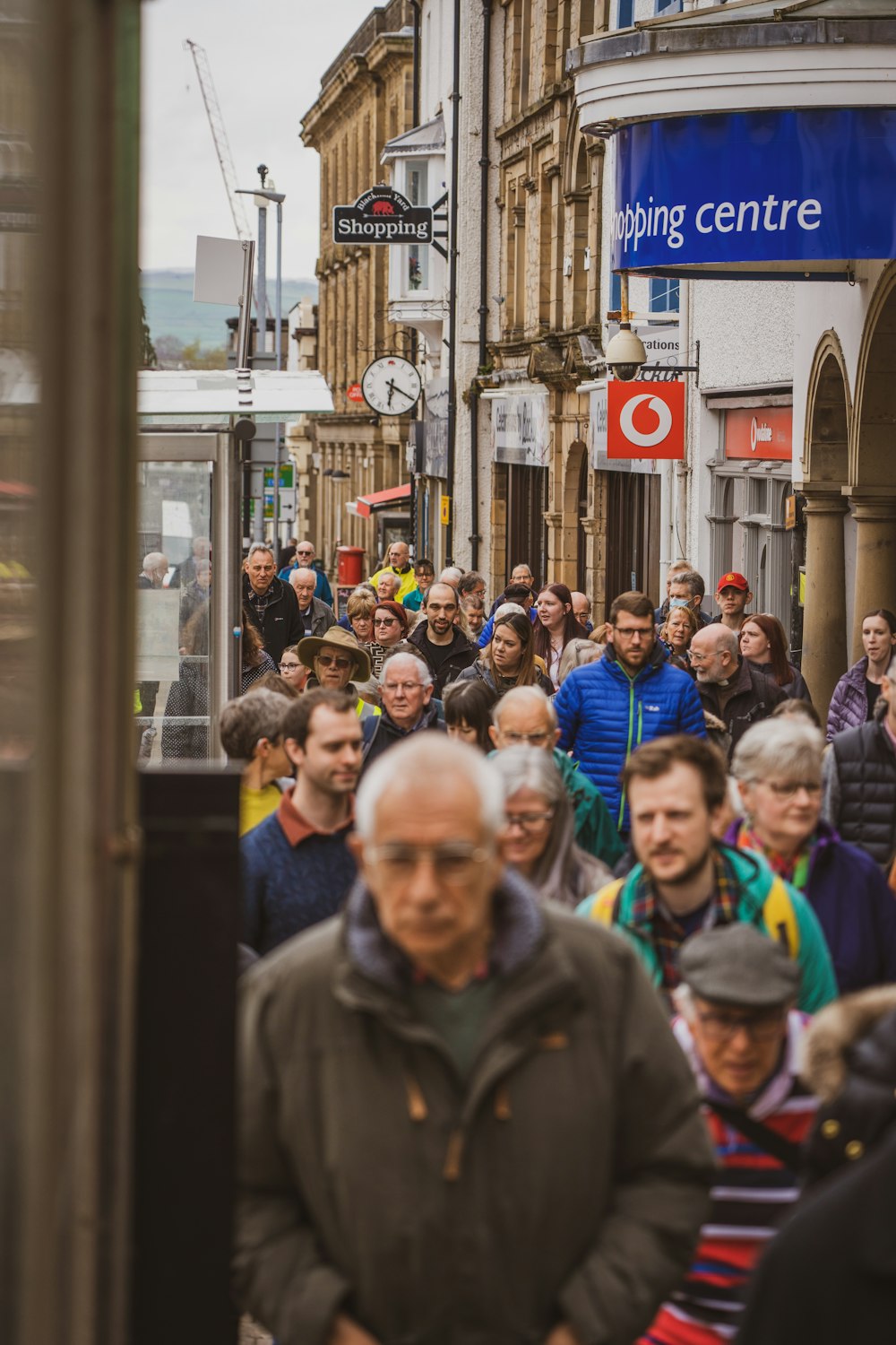 a crowd of people walking down a street next to tall buildings