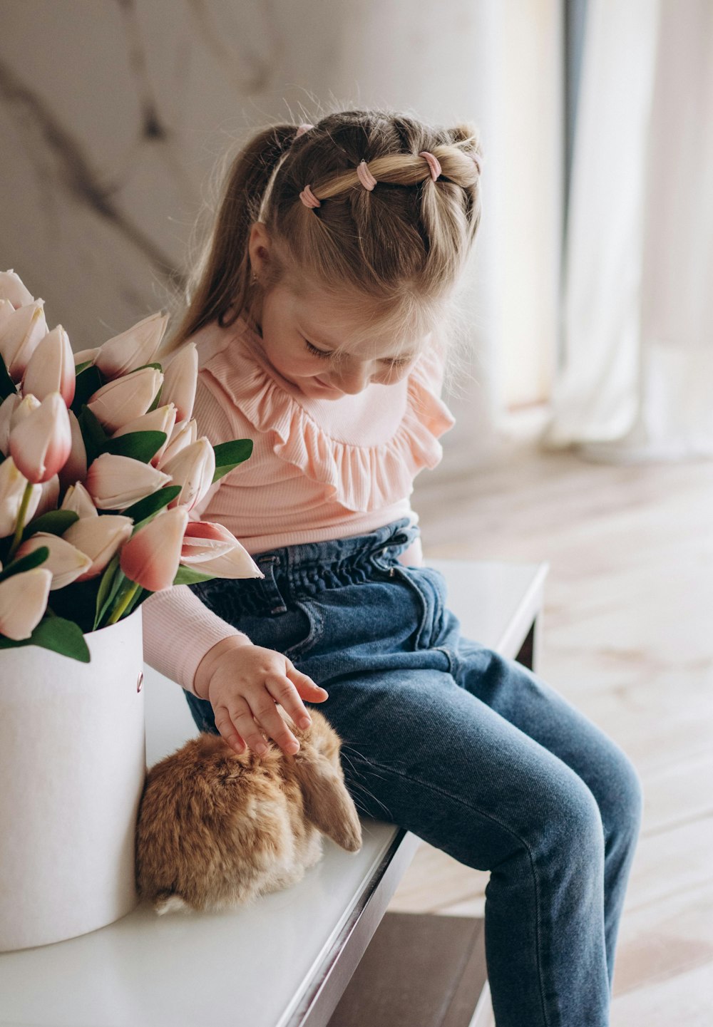 a little girl sitting on a table with a stuffed animal