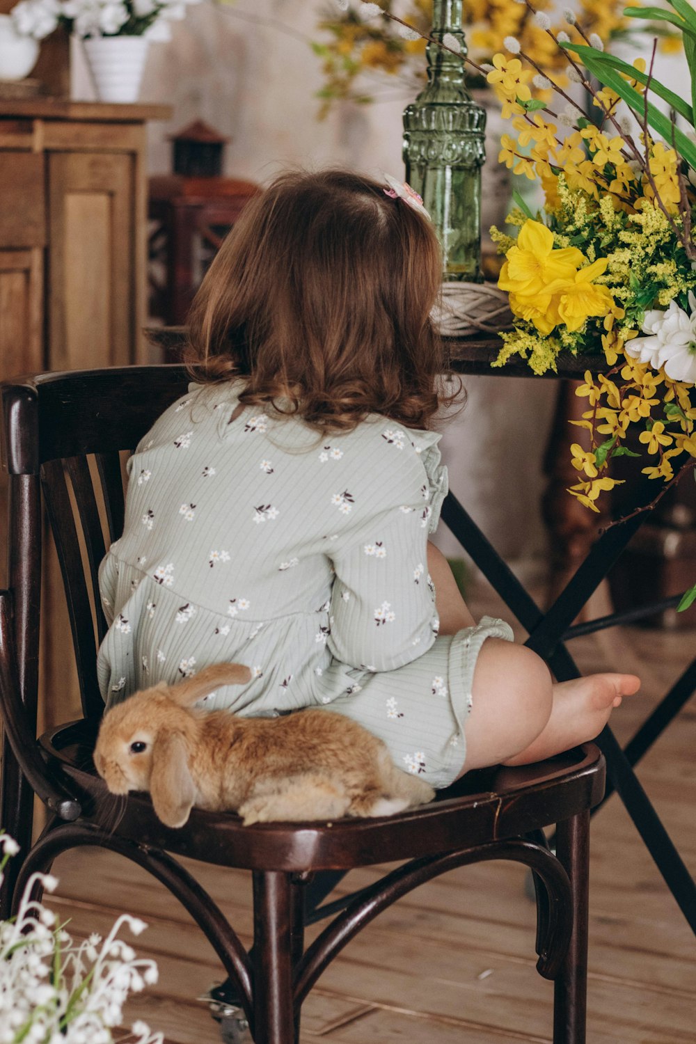 a little girl sitting in a chair with a stuffed animal