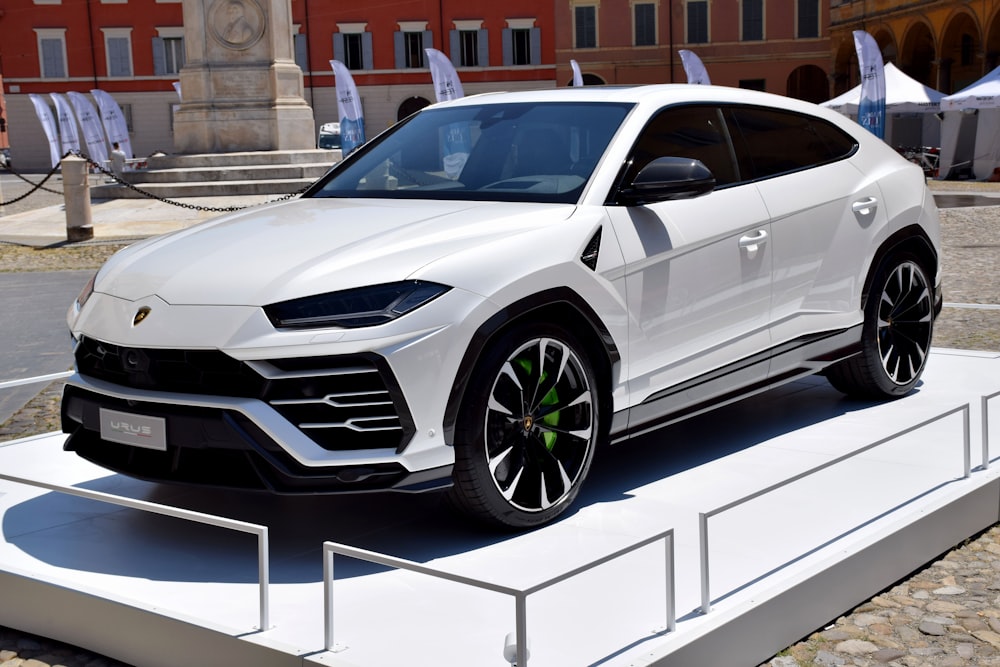 a white lamb suv is on display in front of a building