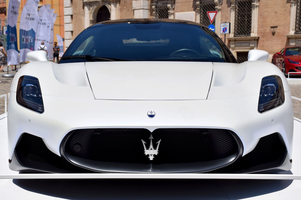 a white masera is parked in front of a building