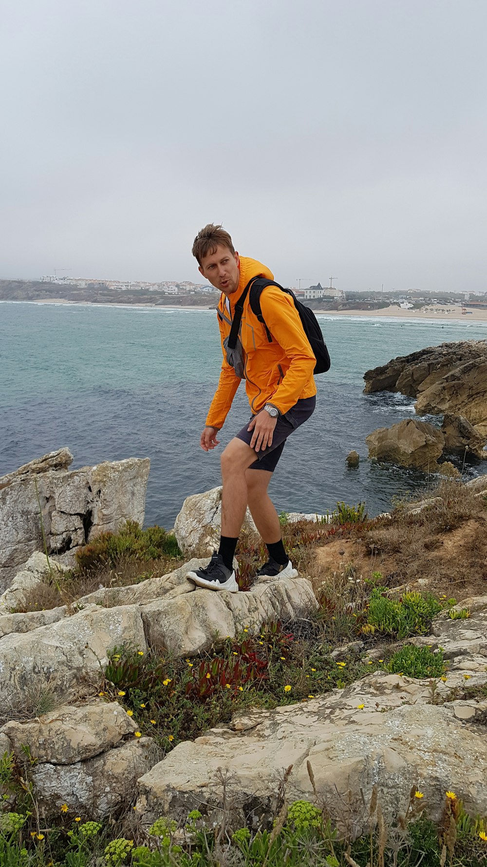 a man standing on top of a rock next to the ocean