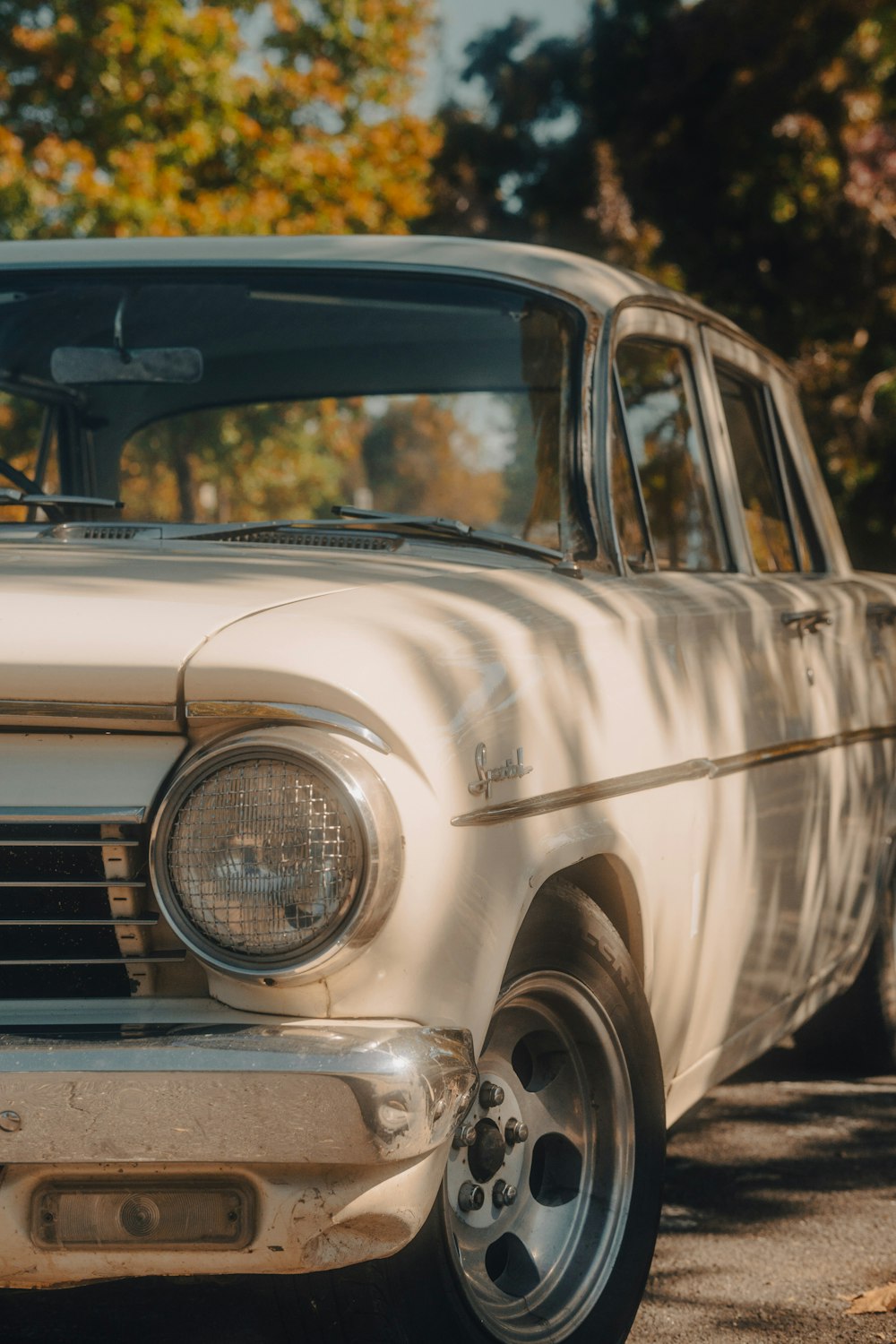 an old white car parked in a parking lot