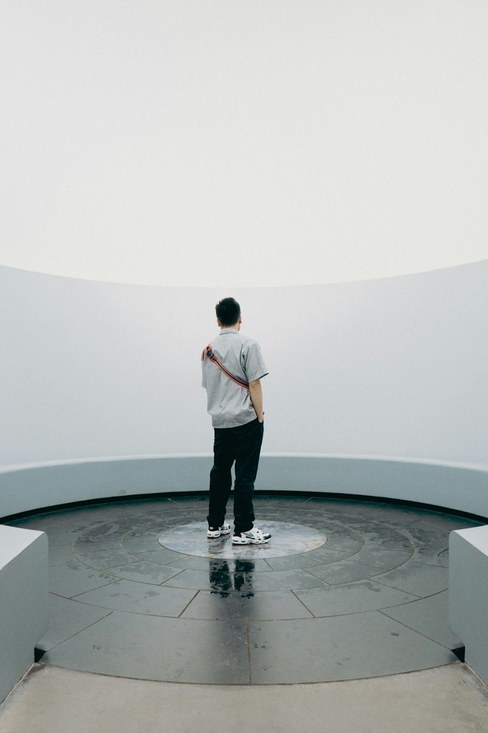 a man standing in a circular room with a skateboard