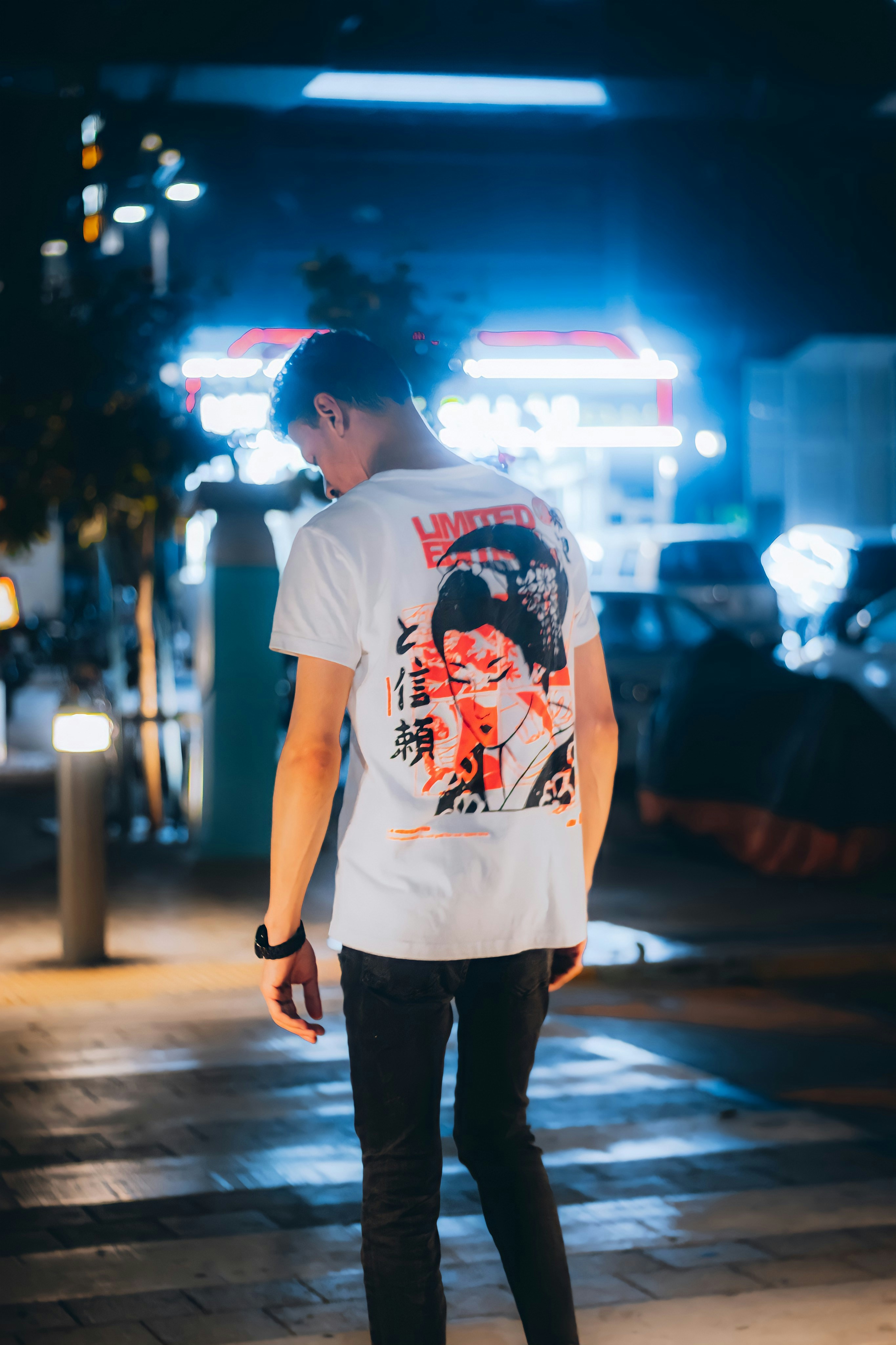 Young man in streetwear holding a custom poster in a dark urban setting with neon lights in background