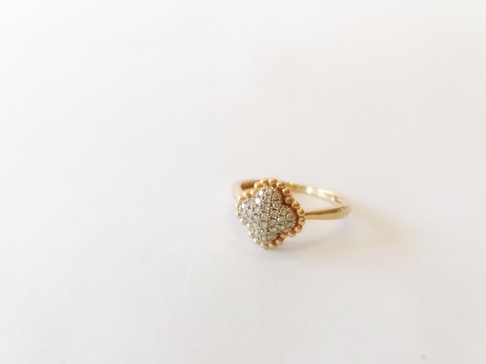 a diamond heart shaped ring on a white surface